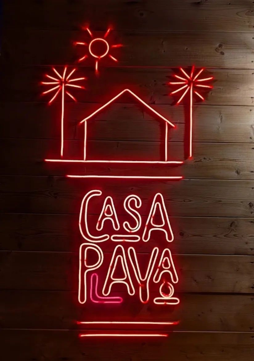 Entrada de Casa Playa con cartel de neón
